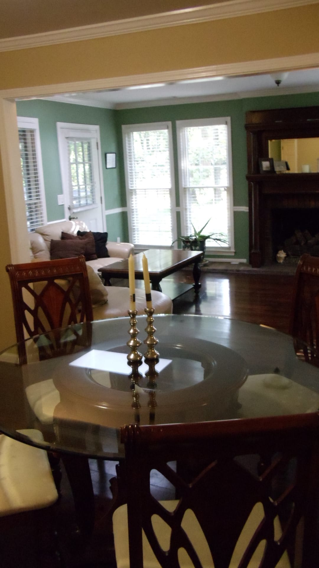 A cozy dining and living area featuring a glass dining table with candles and a comfortable sofa by the window.
