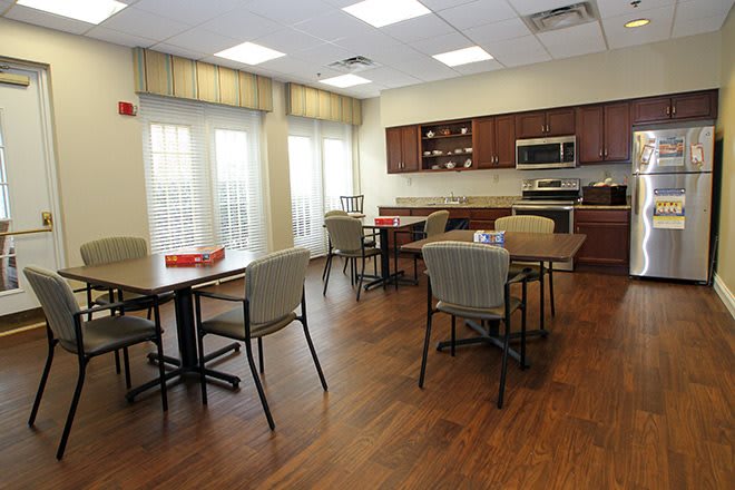 A modern dining area with tables and chairs adjacent to a kitchen.