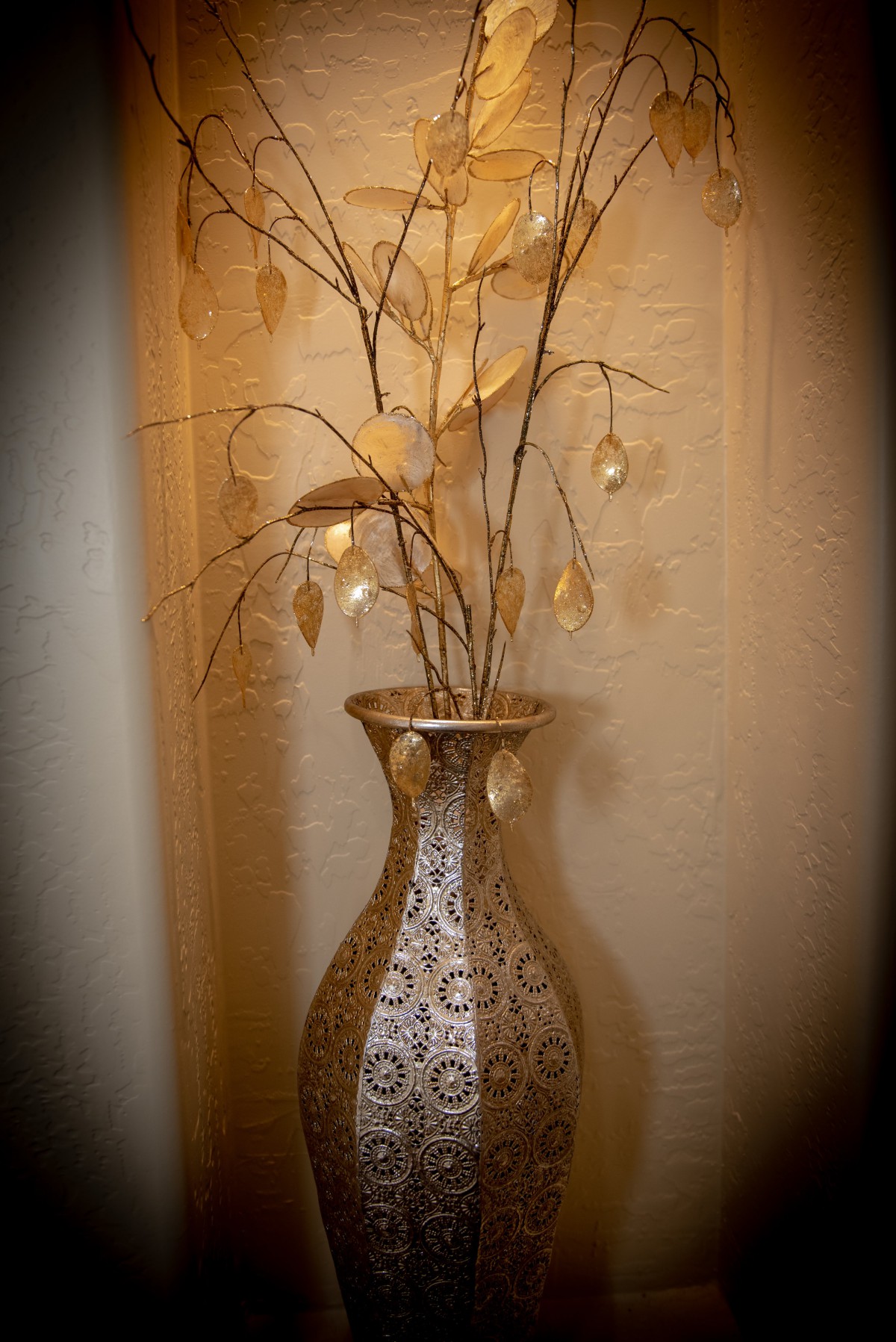 A decorative vase with branches and leaves displayed indoors.