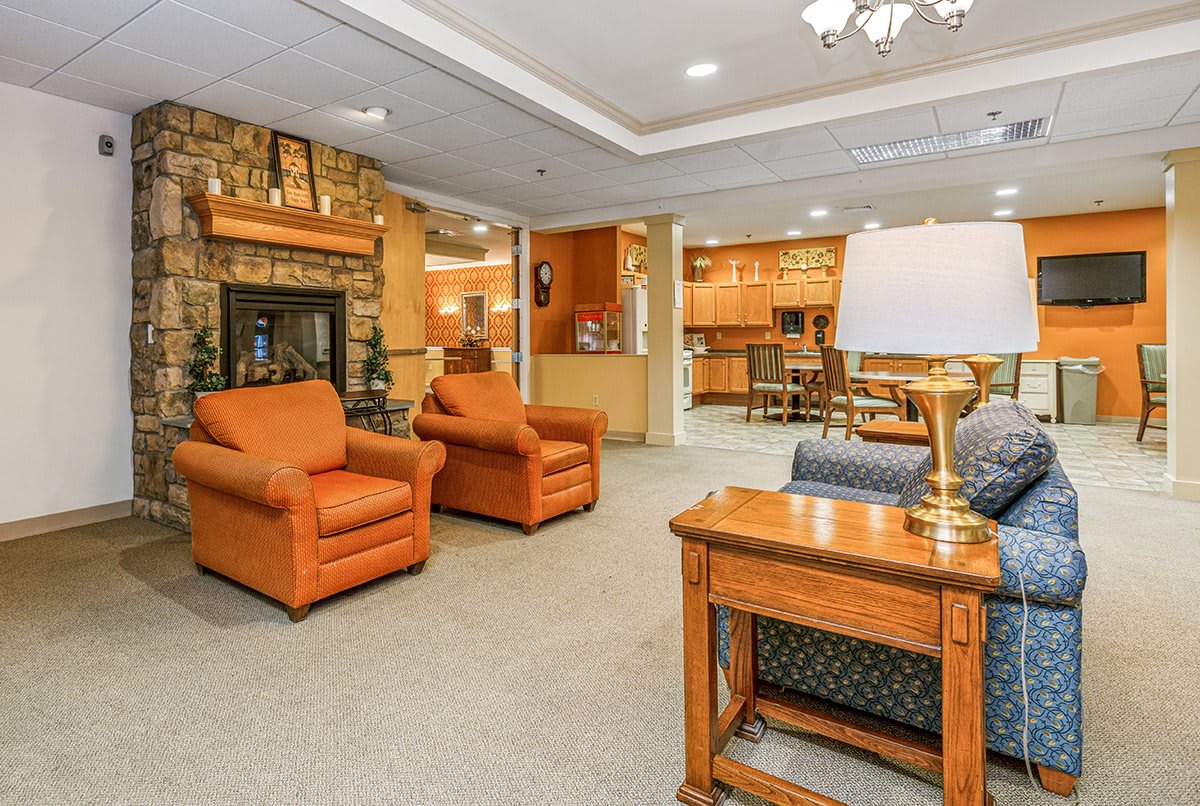 A cozy living room with orange armchairs, a fireplace, and warm lighting.