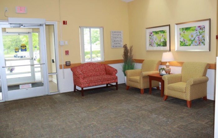 A cozy waiting room with a sofa, chairs, and a table under soft lighting.