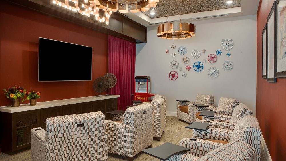 A modern home theater room featuring comfortable seating, a large TV, and a popcorn machine.