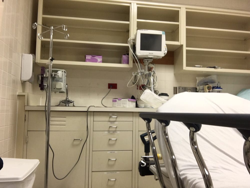 An interior view of a hospital room with medical equipment and a patient bed.