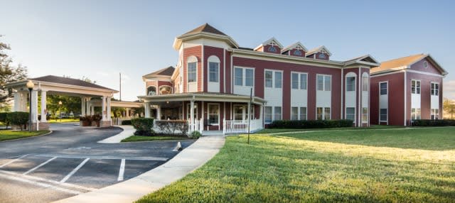A commercial building with a red and white exterior and manicured lawn under a clear blue sky.