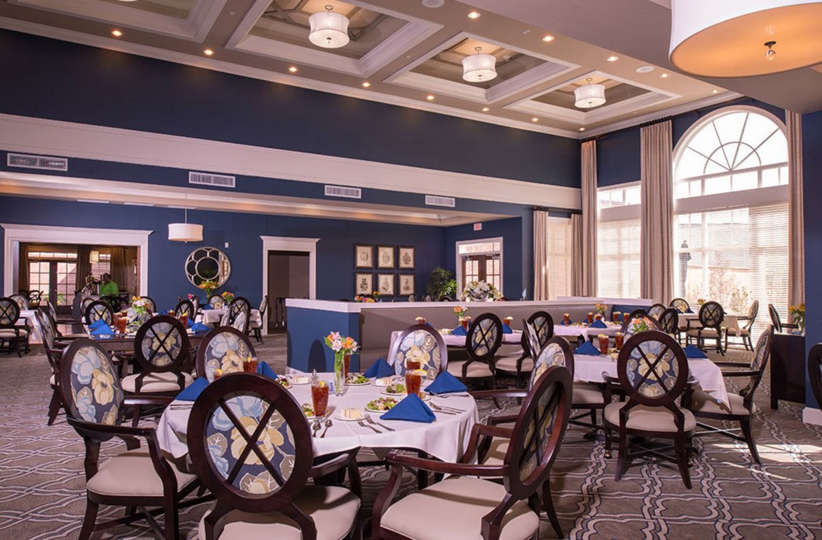 An elegant dining room set up with round tables and formal place settings.