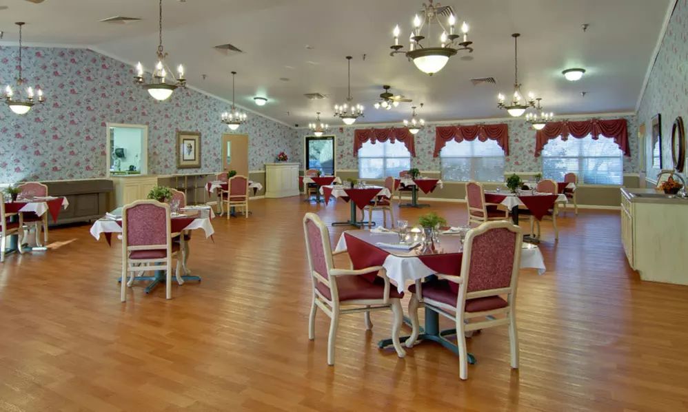 A spacious dining area with elegantly set tables and chandeliers.