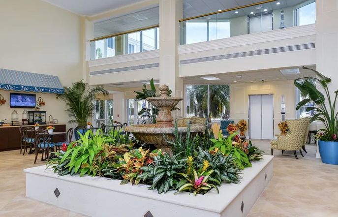 A spacious lobby featuring an elegant indoor fountain surrounded by lush greenery.