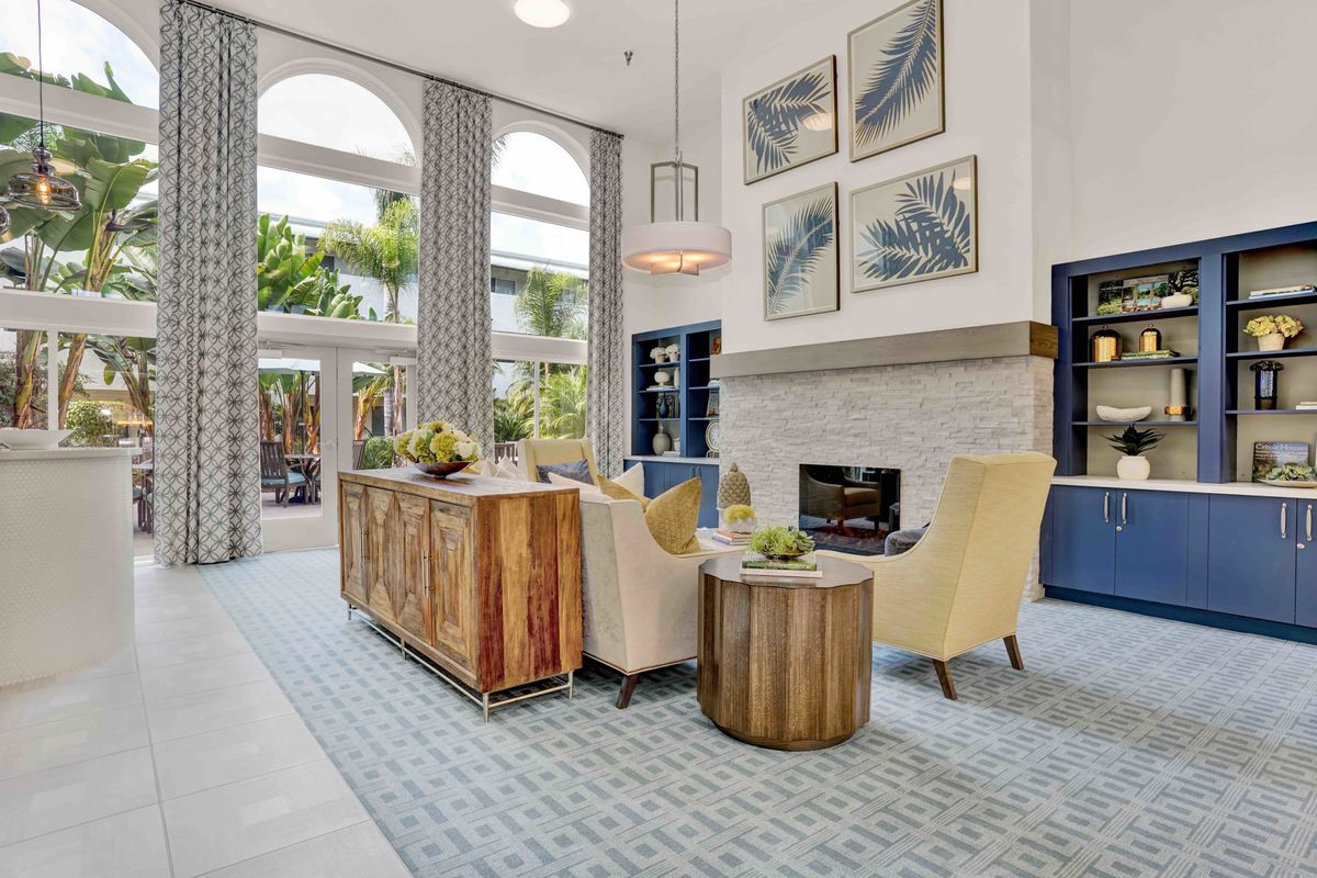 A beautifully designed living room featuring modern furniture, a cozy fireplace, high ceilings, and large windows.
