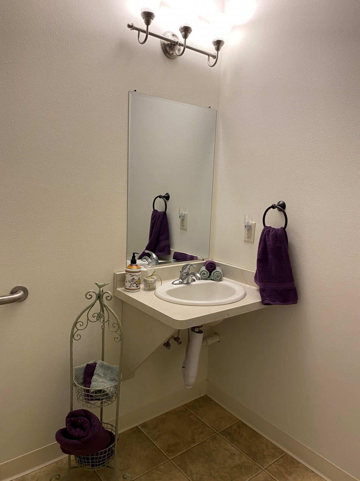 A minimalist bathroom with a wall-mounted sink and purple towels.