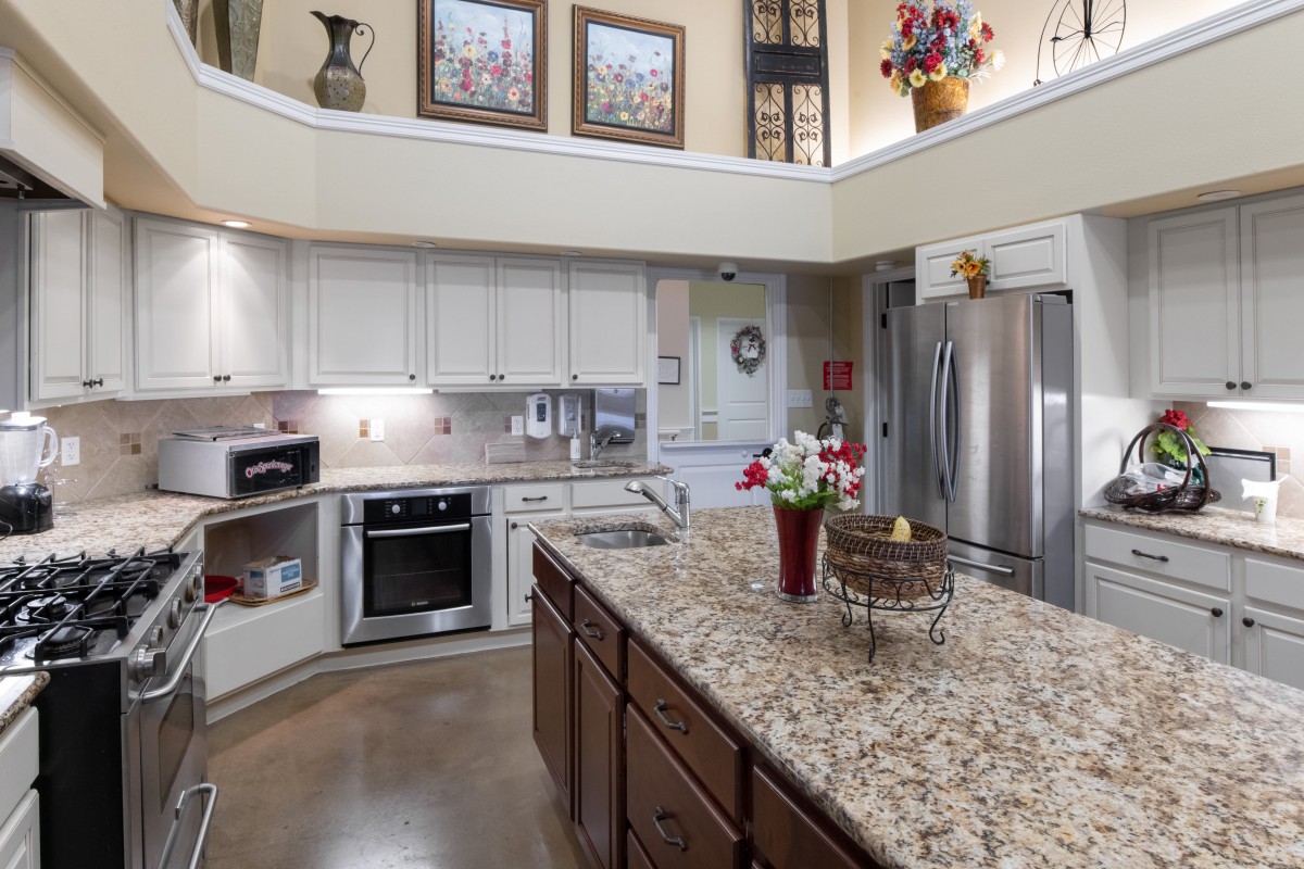 A modern kitchen with white cabinets, granite countertops, and stainless steel appliances.