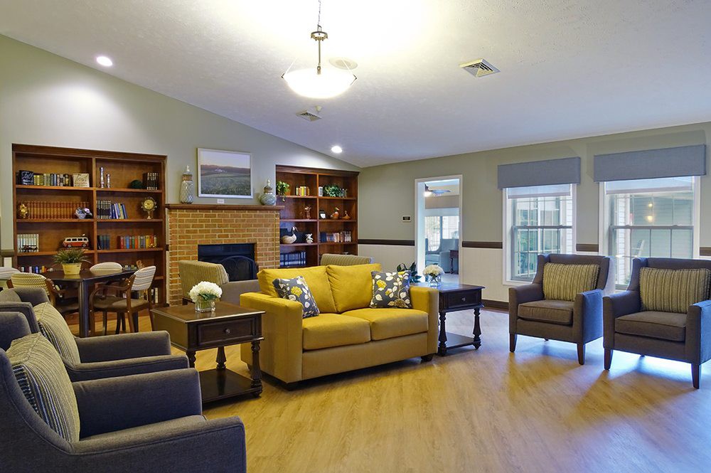 A cozy living room with a yellow sofa and wooden bookshelves.