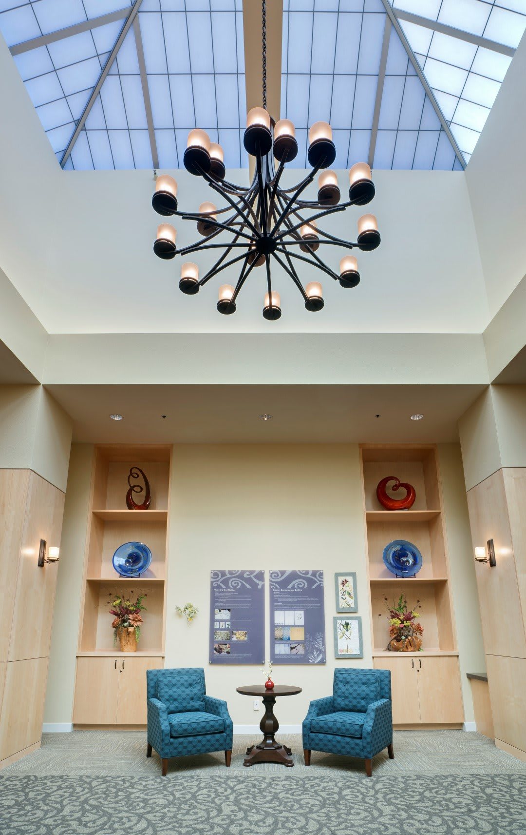 A modern interior space featuring a contemporary chandelier, with decorative shelving and artwork on the walls.