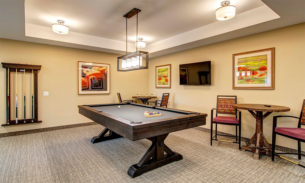 A modern game room featuring a shuffleboard table, contemporary artwork, and comfortable seating.