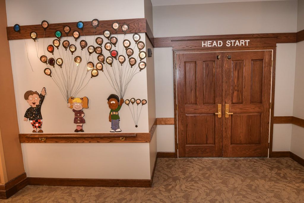 A colorful mural near the entrance to a Head Start program room, featuring children holding balloons.