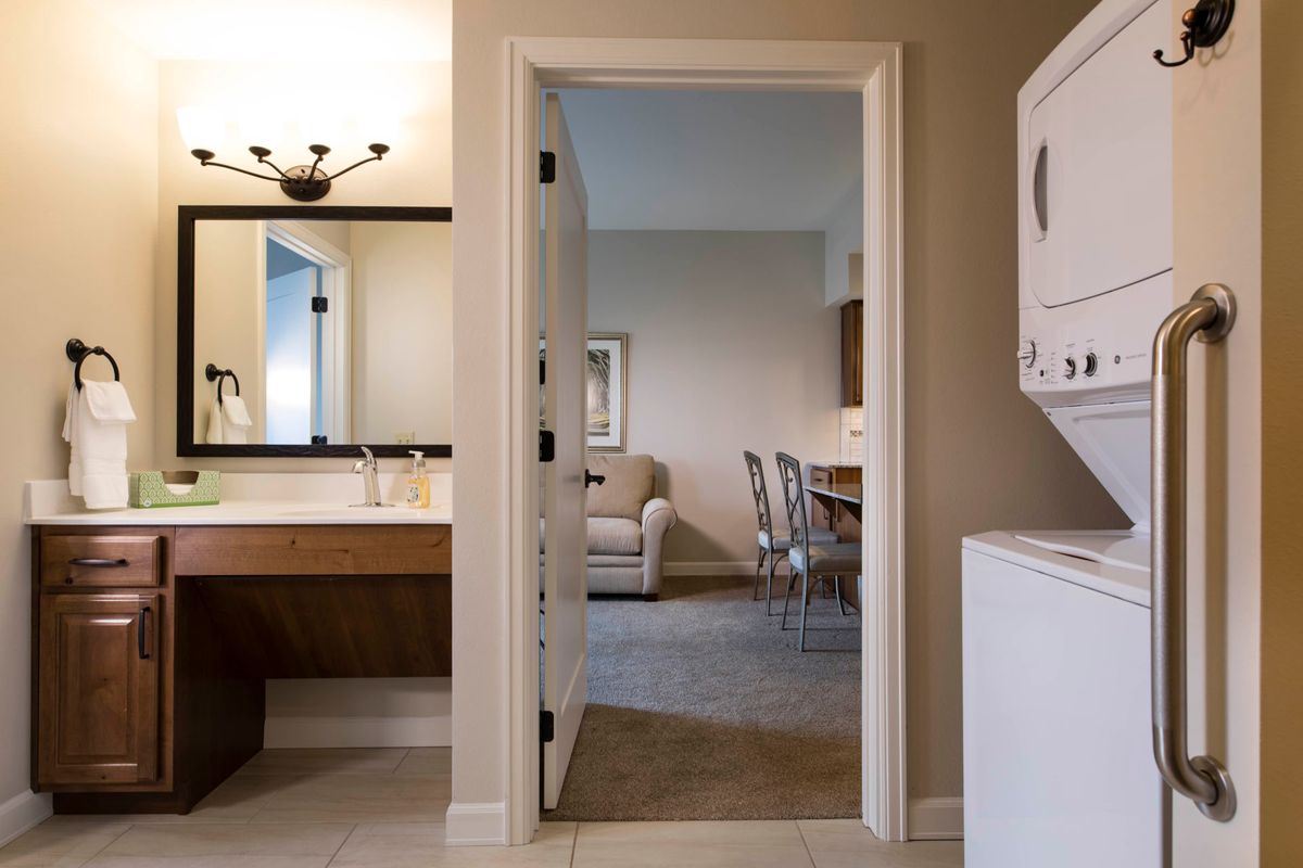 A view from a bathroom into a living room, with a laundry area visible on the right.