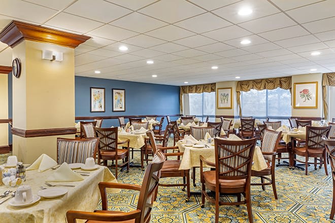 A well-lit dining area with neatly arranged tables and chairs, featuring elegant decor.