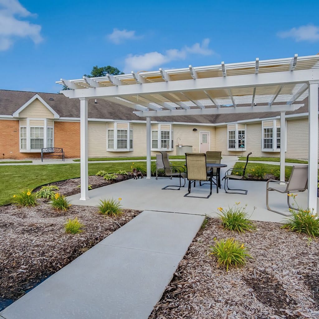 A well-maintained outdoor area featuring a pergola with patio furniture and landscaped garden.