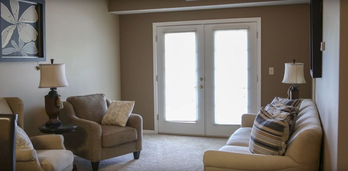 A cozy living room with a sofa and armchair facing bright French doors.