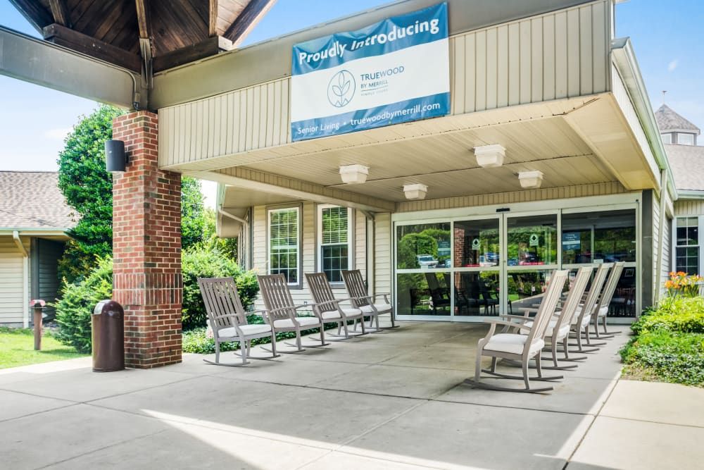 A building entrance with several rocking chairs arranged under a covered area.