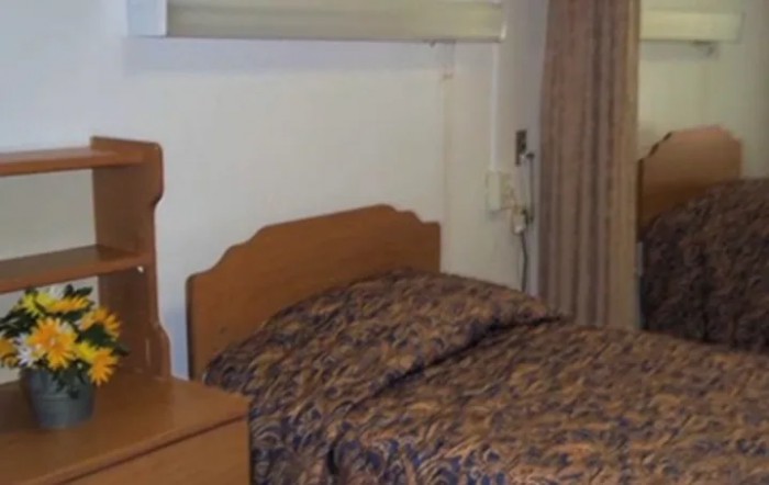 A simple bedroom with a bed, nightstand, and curtains.