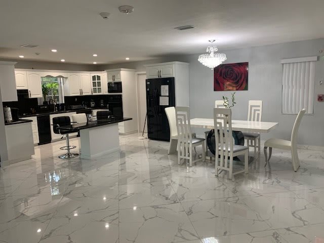 A modern open-concept kitchen and dining area with white decor and marble flooring.