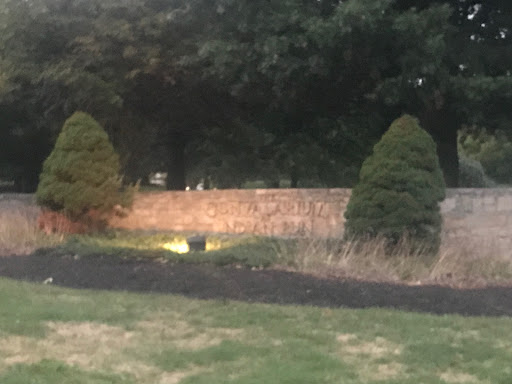 A serene evening view of a landscaped area with trees and a stone wall illuminated by soft lighting.