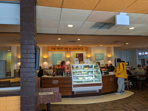 A lively cafe interior with customers enjoying their time and a display of tempting desserts.