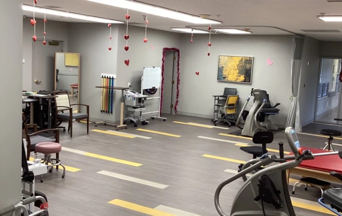 A spacious gym with various exercise equipment and a bright, modern interior design.