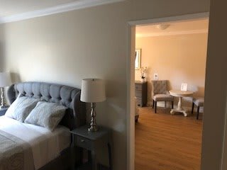 A cozy bedroom with a view into a living area, featuring modern furniture and decor.