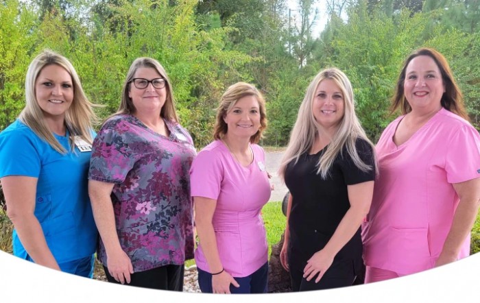 A group of women standing outdoors in casual attire.