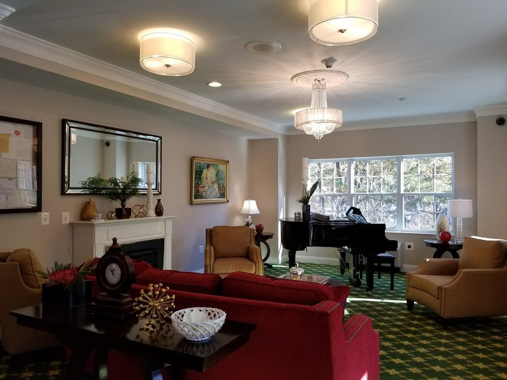 A cozy living room featuring a grand piano and elegant chandeliers.
