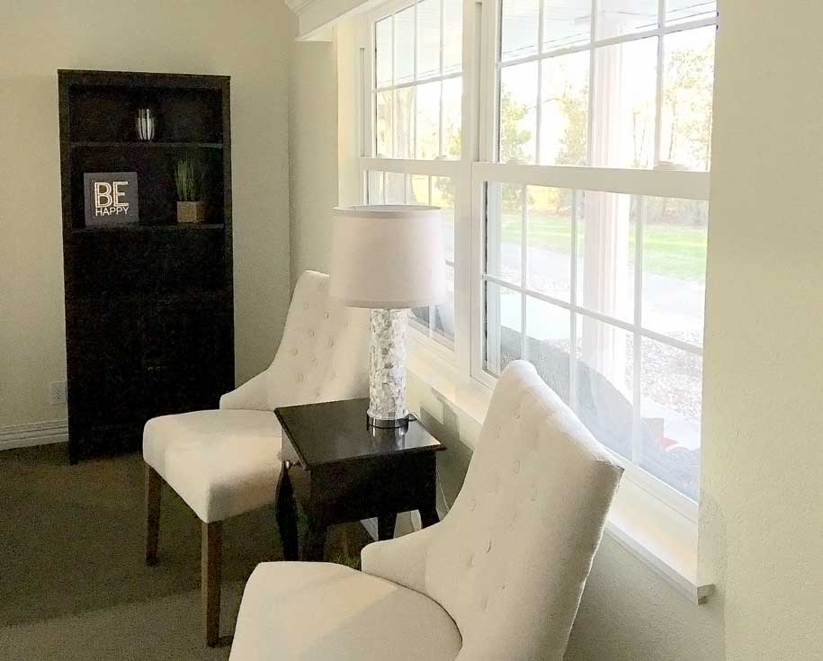 A cozy living room corner with two chairs and a lamp by the window.