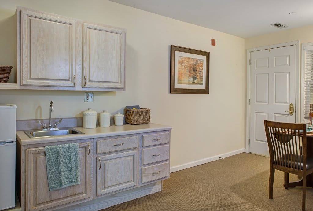 A well-organized kitchen space with light-colored cabinets and a decorative picture on the wall.