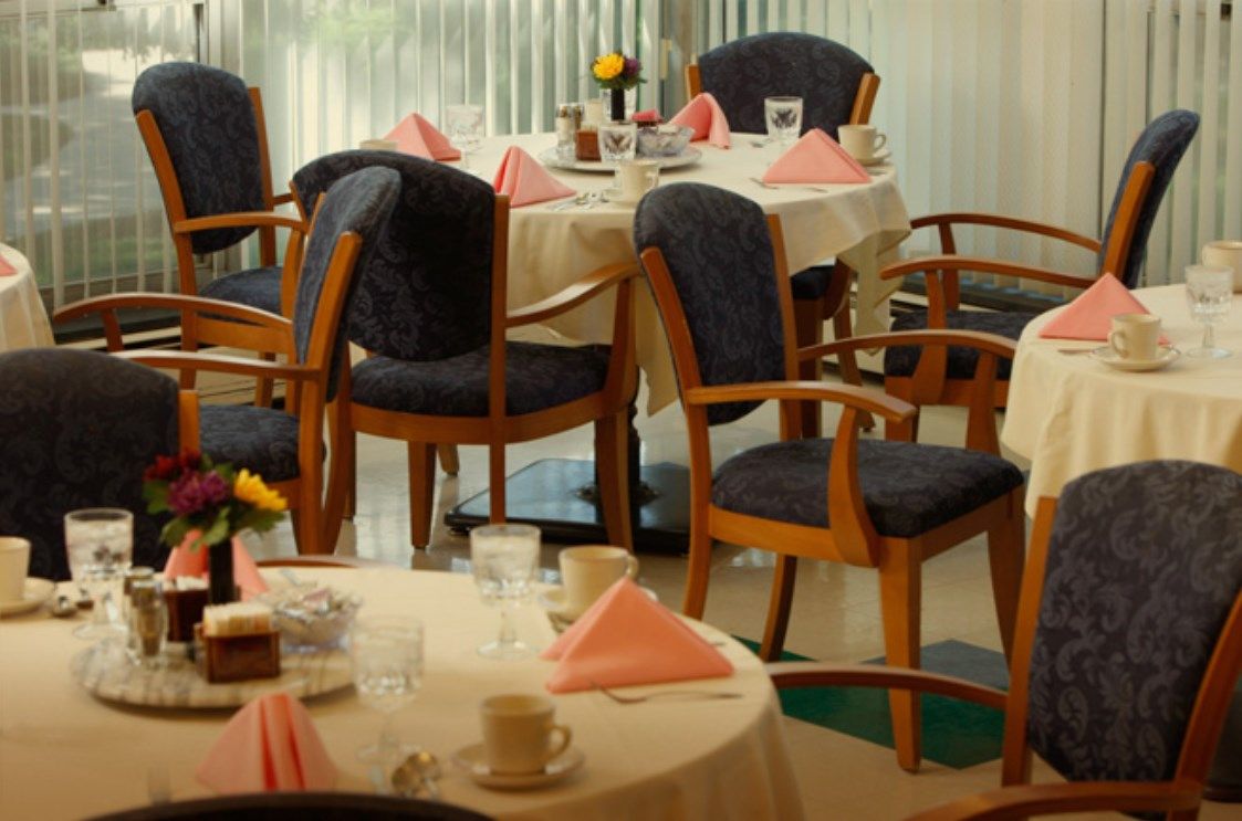 A cozy dining area with elegantly set tables, complete with pink napkins and glasses.