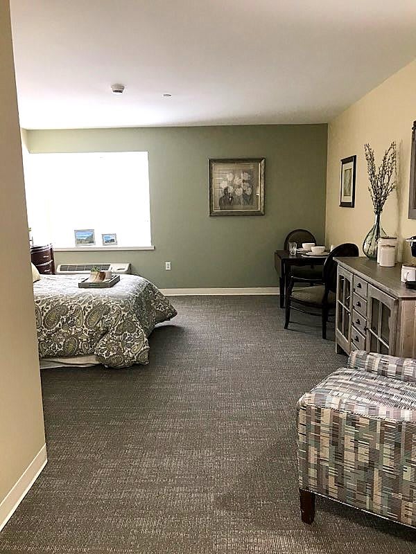A cozy bedroom with a neatly made bed, desk, and decorative elements creating a comfortable atmosphere.