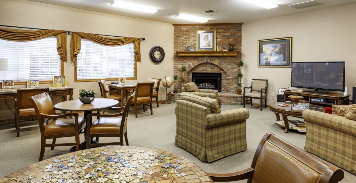 A cozy living room with a fireplace, seating area, tables, and a puzzle in progress.
