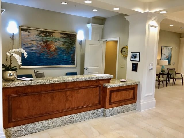 A modern reception desk in an office lobby with artwork on the wall.