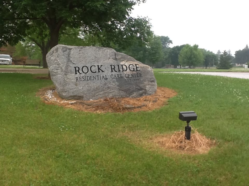 An engraved rock sign for Rock Ridge Residential Community set in a grassy area with trees.