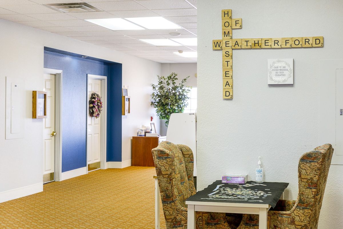 An office interior with wall decor made from Scrabble tiles forming the words 'Home,' 'Weather,' and 'Warmest'.