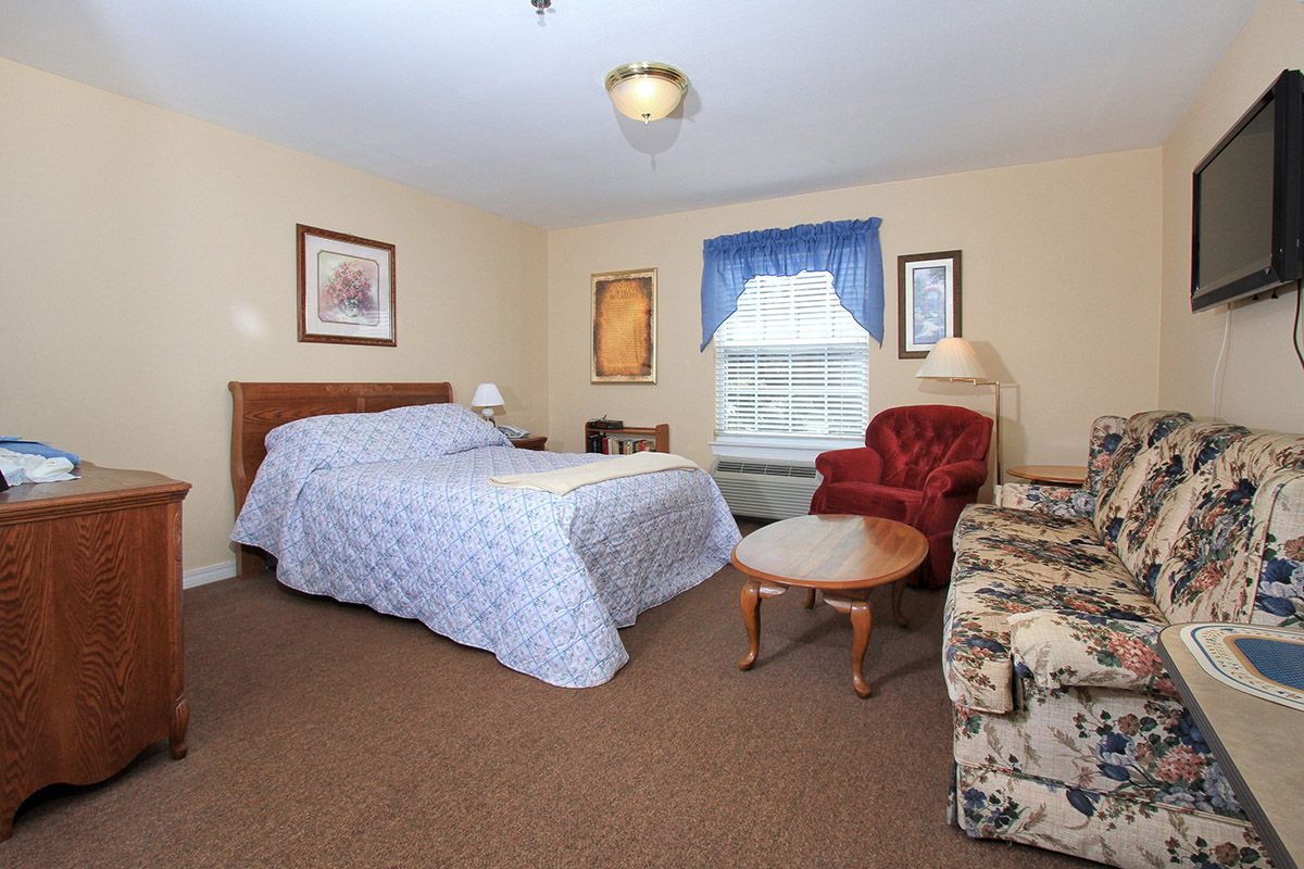 A cozy bedroom with a double bed, armchair, and coffee table, featuring warm decor.