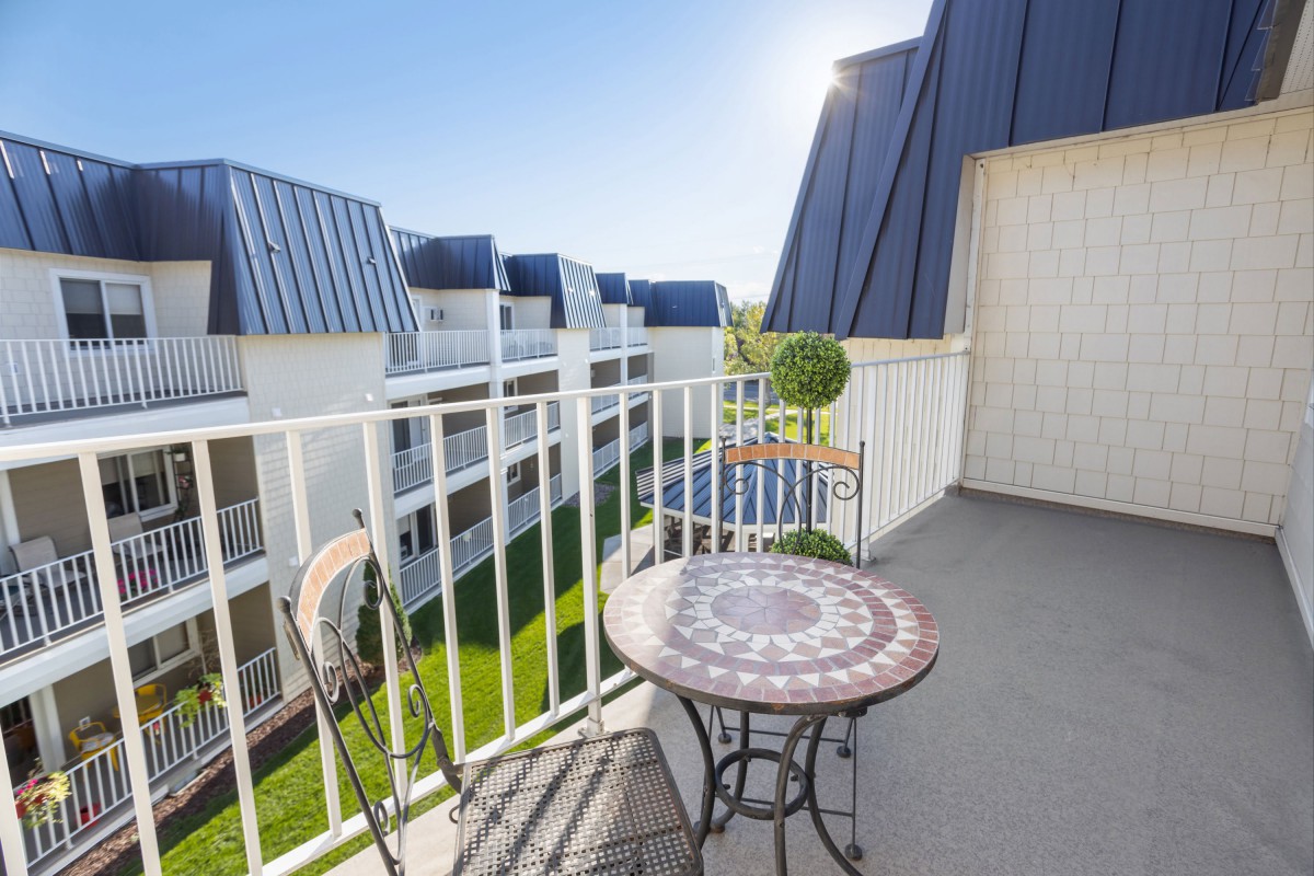 A sunny balcony with a decorative table and chairs overlooking modern buildings.