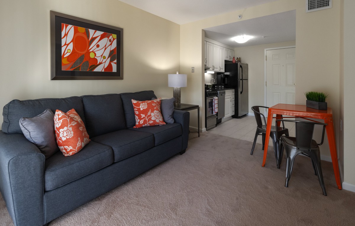 A cozy living area with a sofa, vibrant artwork, and a small kitchenette in the background.