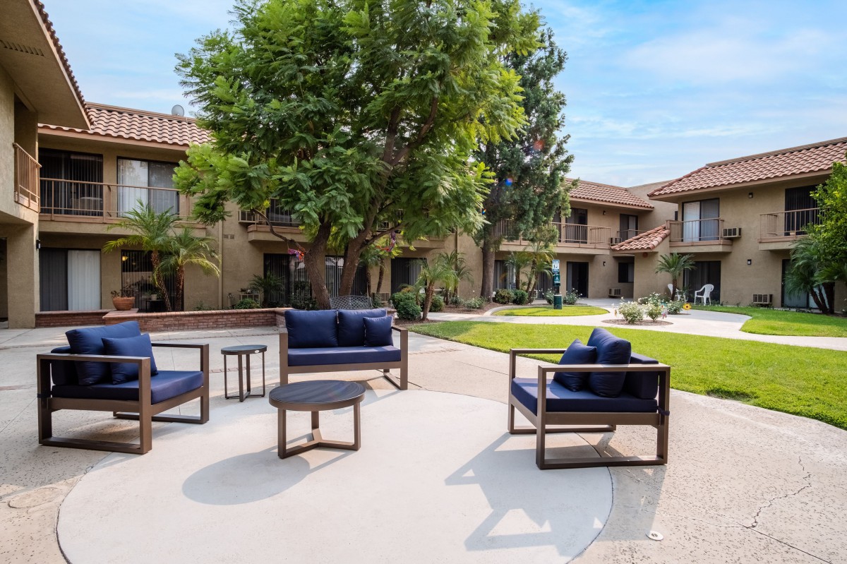 A cozy outdoor courtyard with comfortable seating surrounded by greenery.