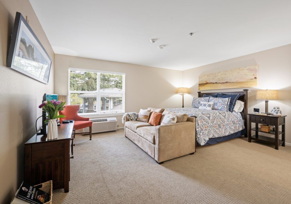 A spacious and well-lit bedroom featuring a large bed, sofa, and elegant decor.