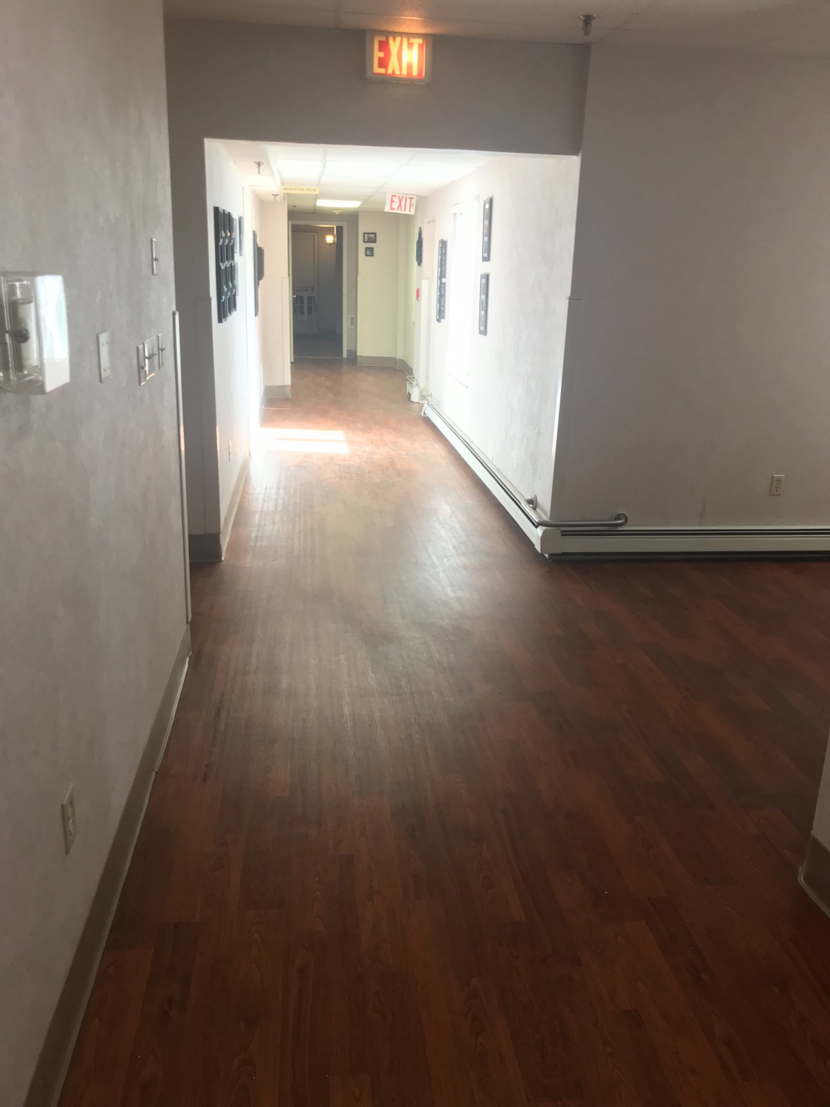 A quiet, empty hallway with wooden flooring and several doorways.