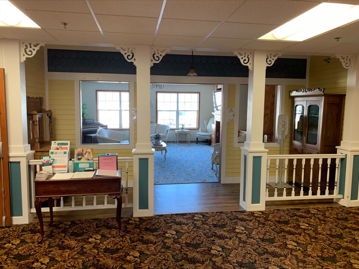 A cozy interior space featuring columns, carpeted floor, and large windows.
