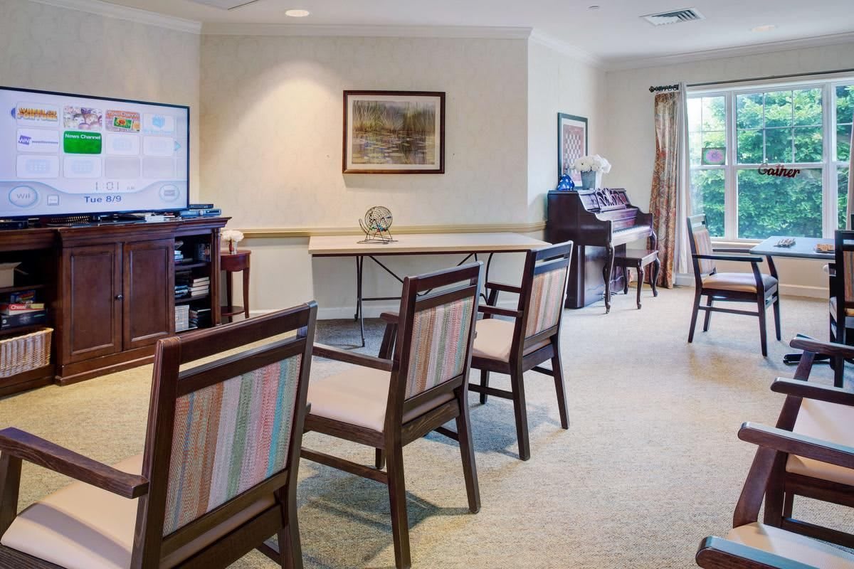A well-lit room with chairs, tables, and a piano.