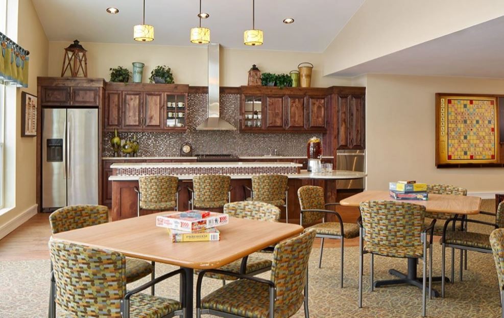 A spacious kitchen and dining area featuring wood cabinetry, multiple seating options, and decorative lighting.