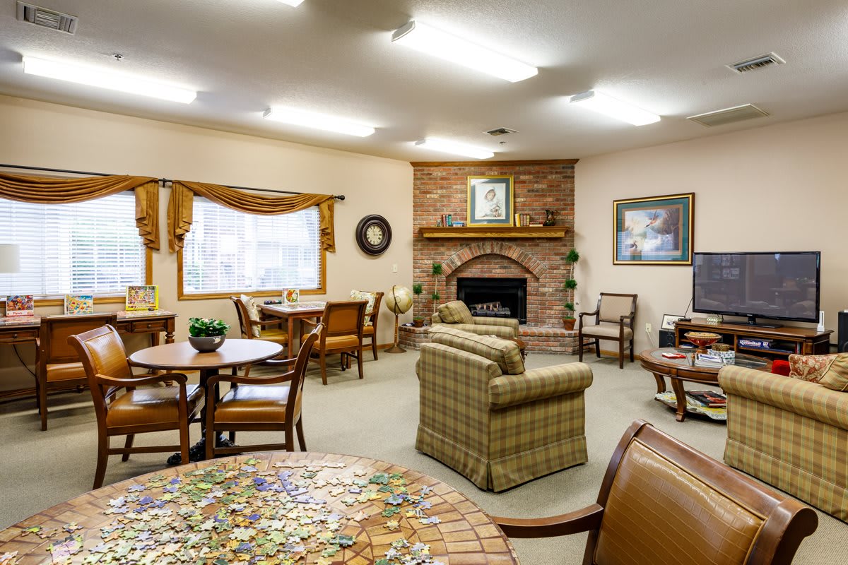 A cozy living room with a fireplace, multiple seating areas, and decorated walls.