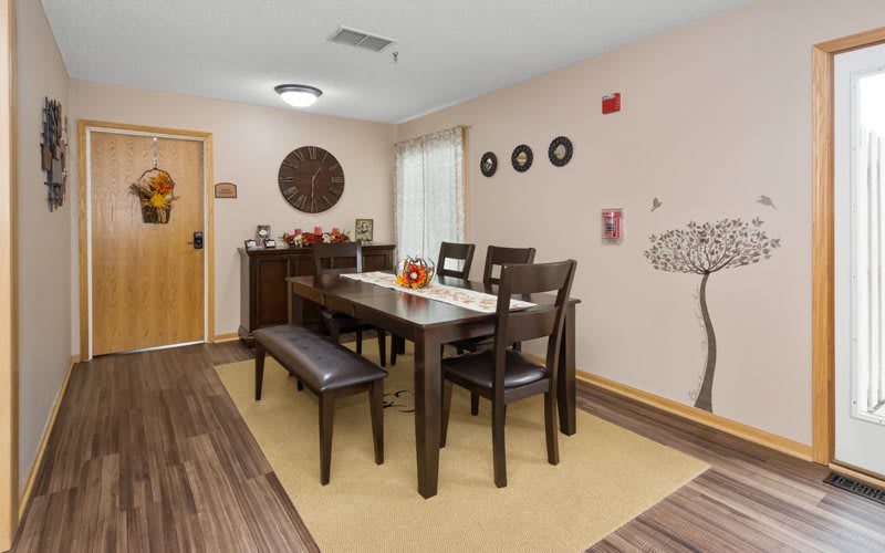 A modern dining room with a wooden table, chairs, and bench, featuring wall art and stylish decor.